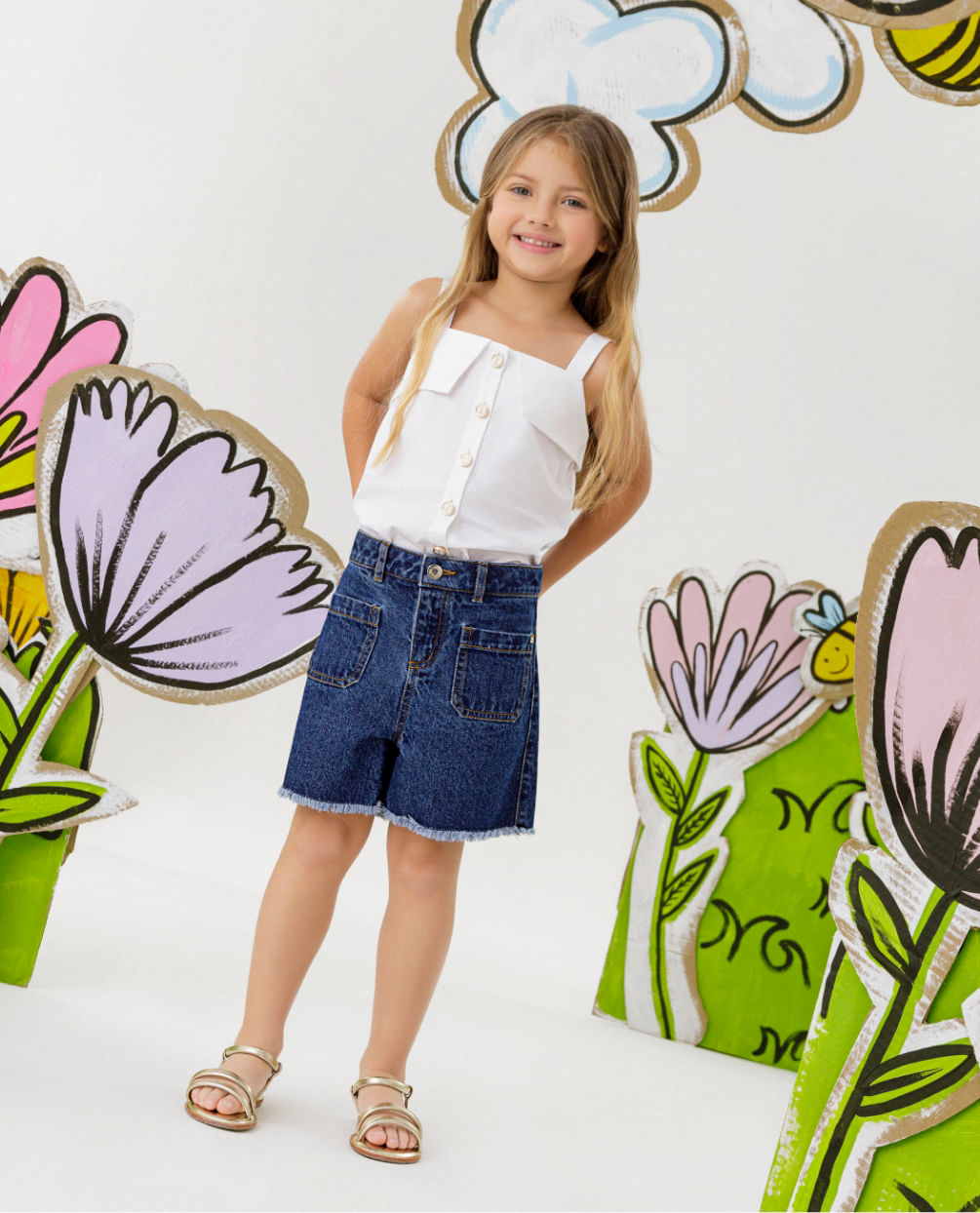 Foto de modelo niña usando blusa color blanco, short de jean para niñas y sandalias color dorado 