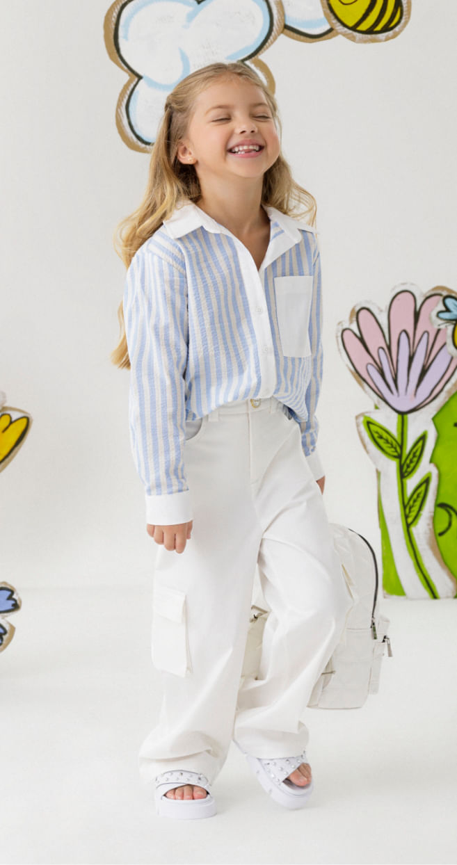 Foto de modelo usando blusa elegante para niña de rayas azules, pantalón cargo blanco y sandalias de niña 