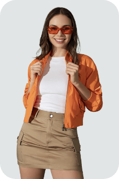 Foto de mujer con chaqueta naranja, blusa blanca, falda corta café y gafas de sol color naranja 